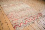 Vintage Moroccan rug corner with dusty blush pink trefoil border and tattered fringe.