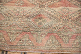 Plush pile of a vintage Moroccan rug displaying abstract trellis and seed motifs in blush and beige.