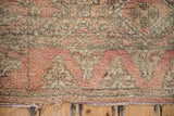 Vintage Moroccan rug showing textured pink pile, trefoil border, and tattered fringe.