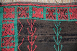 Close-up of the Moroccan rug's turquoise border with red crab-style geometric motifs.