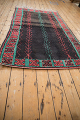 Vintage Moroccan rug from a long angle, showing the central vine pattern and turquoise border.