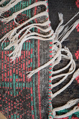 The back of the vintage Moroccan rug showing the flat weave, secured side cord, and braided tassels.