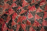 Even, shaggy pile of a Moroccan carpet in varied tones of cherry red and charcoal.