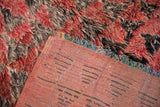 The hand-knotted foundation and thick shaggy pile of a vintage Moroccan carpet shown at the corner.