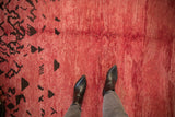 A detailed view of the even, hand-knotted pile in raspberry red with dark chocolate brown abstract patterns.