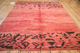 Abstract chocolate brown patterns frame the variegated raspberry red field of a vintage Moroccan carpet.