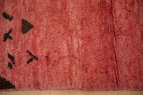 Close-up of the even, nubby pile and abstract brown motifs on a vintage Moroccan carpet in raspberry red.