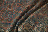 Folded distressed Bibikabad rug, revealing worn texture of Herati pattern, dusty navy and blush.