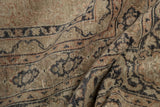 Distressed vintage Sivas carpet showing worn pile and charcoal curvilinear patterns.