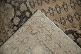 Distressed charcoal and coffee brown pile with visible hand-knotted foundation and side cord.