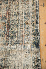 Distressed low-pile texture, revealing muted Herati motifs and a secured side selvage.