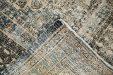 Folded corner of the distressed Bibikabad rug, showing faded Herati design and hand-knotted foundation.