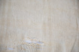 Textured pale sand vintage Turkish hemp kilim showing a rip and hand-stitched repair.