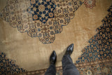 A look down at the distressed texture and navy blue pattern of a vintage Persian Tabriz carpet.