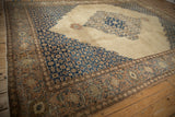 Vintage Tabriz carpet's serrated navy corner spandrel and time-softened camel open field.