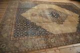 Decorative low pile and serrated navy spandrels of a vintage Tabriz carpet from an angle.