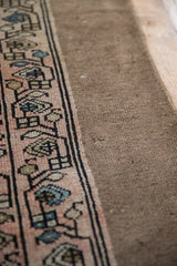 Angled view of the antique distressed Persian runner's blush geometric border and low pile.