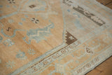 Close-up of a vintage distressed Oushak carpet corner showcasing abrashed sand field and blue cloudband motifs.