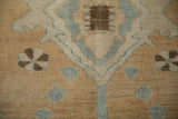 Distressed Oushak pile with stylized cloudband and floral motifs in sand, ivory, blue, and brown.