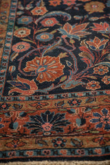Vintage Dargezine carpet detail, showing brick red border with blue accents and navy field florals.