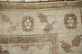 Corner detail of a distressed Kars carpet showing the short pile and floral-fern leaf border.
