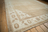 Angled detail of a vintage Kars rug corner, showing the floral border and low pile in neutral tones.