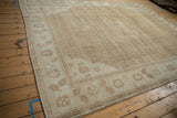 Angled view of a distressed Kars carpet showing abrashes across its sand and pale brown field.