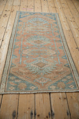 Distressed Hamadan runner corner showing faded cantaloupe and blue geometric motifs with visible wear.