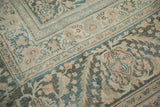 Distressed vintage Khorassan carpet showing muted beige, teal, and peach floral patterns.