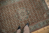 Overhead perspective on a distressed antique Malayer rug, focusing on the starburst medallion and rust field.