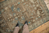 Angled view highlighting the decorative wear and faded turquoise accents on a brown vintage rug.