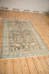 High-angle view of a distressed Hamadan rug with coffee brown and turquoise accents.