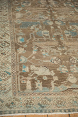 Corner detail of a distressed Hamadan rug highlighting its low pile and faded turquoise patterns.