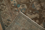 Corner of a distressed Hamadan rug folded to show the hand-knotted back and secured side selvage.