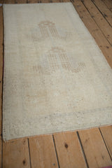 Faint weeping willow motifs, distressed pile, and intact side selvage of the Oushak rug.