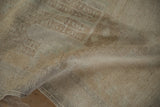 Distressed low pile texture of a vintage Oushak rug, showing muted cream and sand tones.