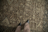 Abrashes across a Mehrivan carpet's low pile, revealing muted brown and dusty blue floral patterns.