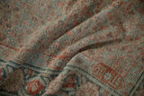 Draped antique Malayer rug showing worn pile, muted terracotta, and dusty teal floral motifs.