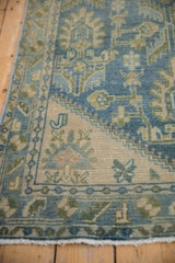 Distressed texture of vintage Hamadan runner showing dusty blue vine border and palmette motifs.