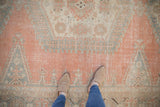 Distressed Veece carpet in faded cantaloupe, grey-blue, and ivory with visible foundation wear.