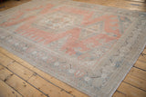 Distressed Veece carpet corner, showing dusty cantaloupe, faded denim, ivory motifs, wear to knot heads.
