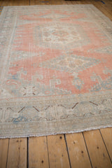 Fringed edge and distressed pile of a vintage Veece carpet, revealing faded cantaloupe and blue tones.