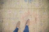 Distressed Afghani Oushak rug texture showing pale lime, dusty rose, and sky blue motifs.