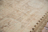 Distressed Afghani Oushak carpet pile, showing soft ivory, beige wool, shearing, and braided selvage.
