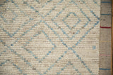 Textured ivory and powder blue Moroccan diamond pattern detail with woven side selvage.