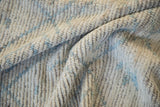 Distressed Afghani Moroccan carpet pile showing ivory, powder blue, and visible foundation.
