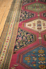 Angled close-up of antique Karabagh runner's border and deep pink floral field.