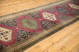 Antique Karabagh runner with emerald green floral medallion, deep red field, and sapphire blue detail.