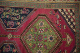 Emerald green floral medallion against a purple main field on an antique Karabagh runner.