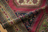Folded antique Karabagh runner detail: berry red field and floral sapphire blue, green borders.